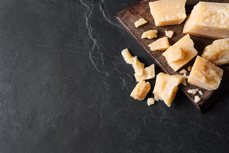 Pieces of delicious parmesan cheese on black table, top view. Space for textの写真素材