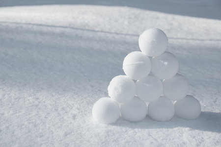 Pyramid of perfect snowballs on snow outdoors. Space for textの写真素材