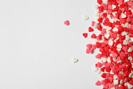 Bright heart shaped sprinkles on white background, flat lay. Space for textの写真素材