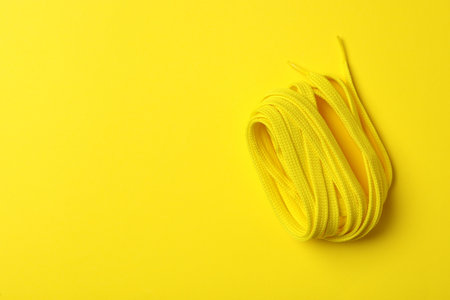 Shoelace on yellow background, top view. Space for textの写真素材