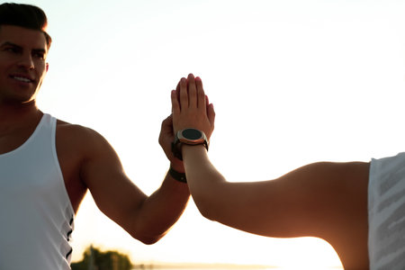 Couple with fitness trackers giving each other high fives after training outdoors, closeupの写真素材