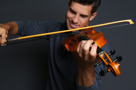 Happy man playing violin on black background, focus on handの写真素材