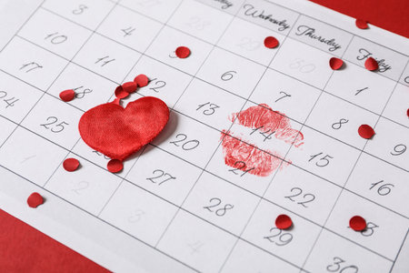 Calendar with marked Valentine's Day, confetti and heart on red background, closeupの写真素材