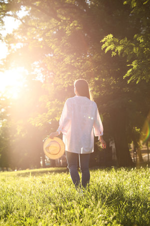 Young woman with straw hat outdoors on sunny day, back viewの写真素材