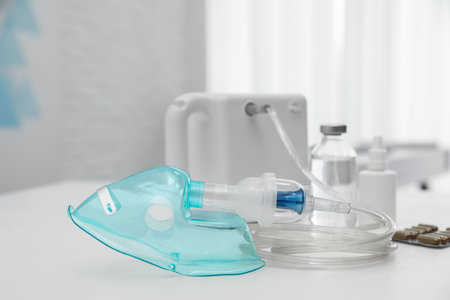 Modern nebulizer with face mask and medicines on white table indoors. Equipment for inhalationの写真素材