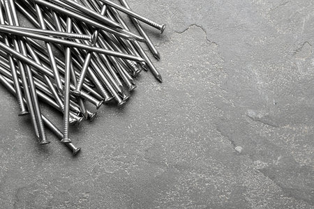 Pile of metal nails on gray stone background, flat lay. Space for textの写真素材