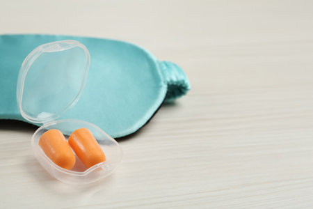 Pair of ear plugs and sleeping mask on white wooden background. Space for textの写真素材