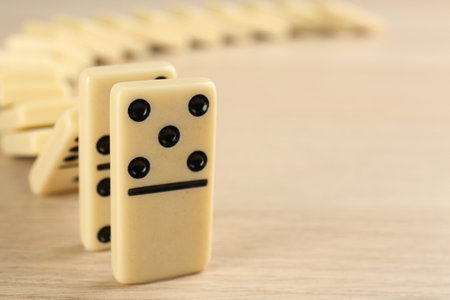 White domino tiles falling on wooden table, closeup. Space for textの写真素材