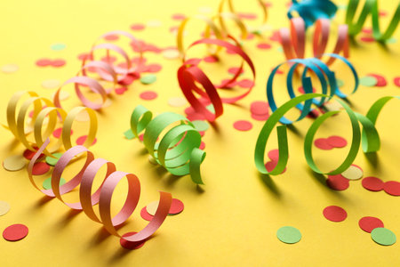 Colorful serpentine streamers and confetti on yellow backgroundの写真素材