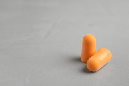 Pair of orange ear plugs on gray background. Space for textの写真素材