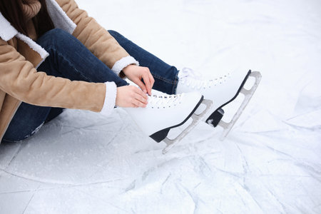 Woman lacing figure skate while sitting on ice, closeupの写真素材