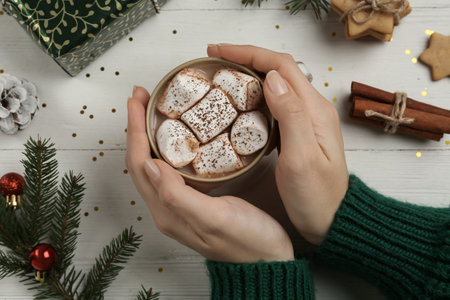 Woman with cup of delicious marshmallow cocoa at white wooden table, top viewの写真素材