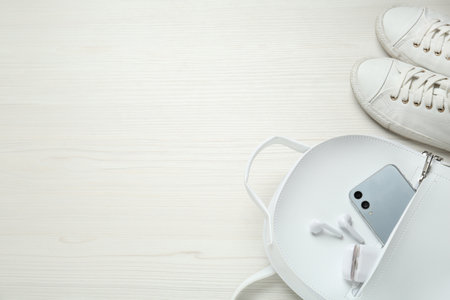 Backpack, sneakers, mobile phone and earphones on white wooden background, above view. Space for textの写真素材