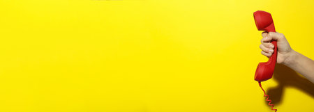 hotline service. Woman with telephone receiver and space for text on yellow background, banner designの写真素材