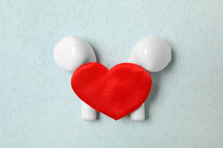 Modern earphones and red heart on turquoise background, flat lay. Listening love music songsの写真素材