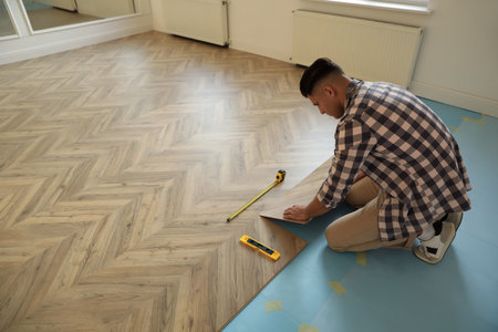 Professional worker installing new parquet flooring indoorsの写真素材