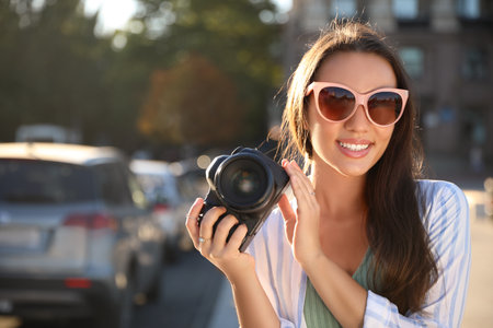 Young photographer with professional camera outdoors. Space for text