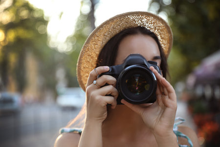 Young photographer taking picture with professional camera outdoorsの写真素材