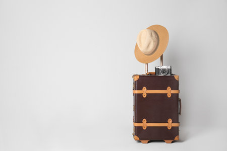 Vintage travel suitcase with hat and camera on light gray background, space for text. summer holidaysの写真素材