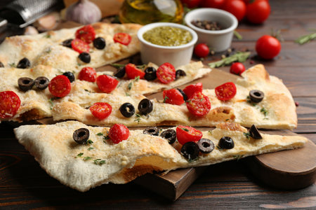 Focaccia bread with olives and tomatoes on wooden table, closeupの写真素材