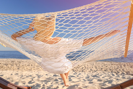 Young woman relaxing in hammock on the beachの写真素材