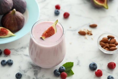 Delicious fig smoothie in glass on white marble tableの写真素材