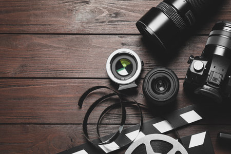 Flat lay composition with camera and video production equipment on brown wooden background. Space...