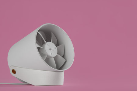 Modern electric fan on pink background. Space for textの写真素材