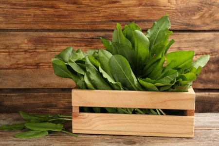 Fresh green sorrel leaves in crate on wooden tableの写真素材