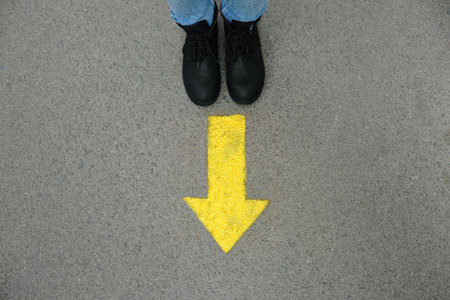 Person standing near arrow on asphalt, top viewの写真素材