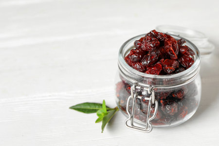 Tasty dried cranberries and leaves on white table. Space for textの写真素材