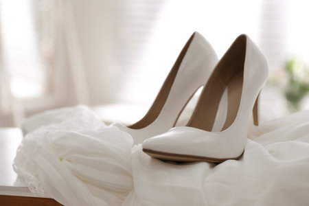 Pair of white high heel shoes and wedding dress on table indoorsの写真素材