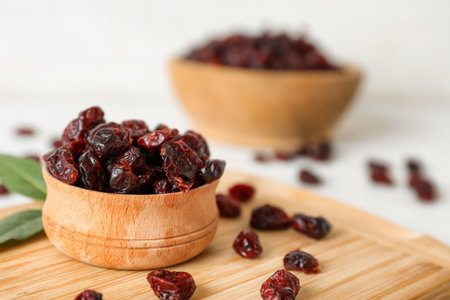 Tasty dried cranberries in bowl on wooden board. Space for textの写真素材