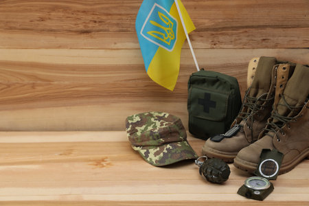 MYKOLAIV, UKRAINE - SEPTEMBER 26, 2020: Tactical gear and Ukrainian flag on wooden background. Space for textのeditorial素材