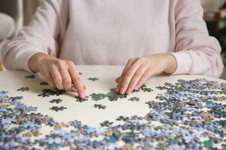 Young woman playing with puzzles at table, closeupの写真素材