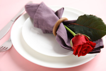 Beautiful table setting with red flower on pink background. Valentine's day romantic dinnerの写真素材