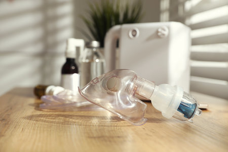 Face mask near nebulizer and medications on wooden table indoors. Inhalation equipmentの写真素材