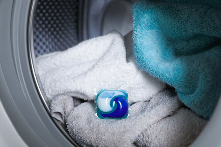Laundry detergent capsule and towels in washing machine drum, closeup viewの写真素材