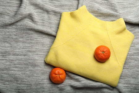 Yellow warm sweater with tangerines on gray plaid, flat lay. Space for textの写真素材