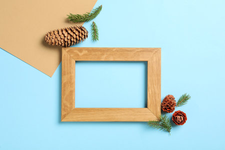 Pinecones, fir branches and wooden frame on color background, flat lay. Space for textの写真素材