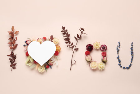 Phrase I Love You made of flowers and paper heart on beige background, flat layの写真素材