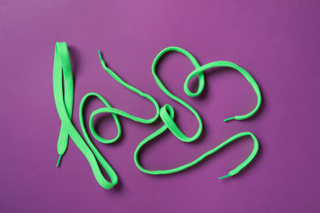 Green shoelaces on purple background, flat layの写真素材