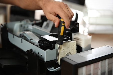 Repairman with screwdriver fixing modern printer, closeupの写真素材