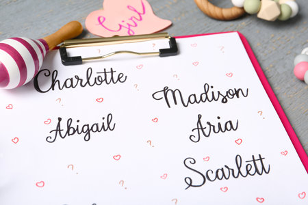 Clipboard with different baby names and toys on gray table, closeupの写真素材