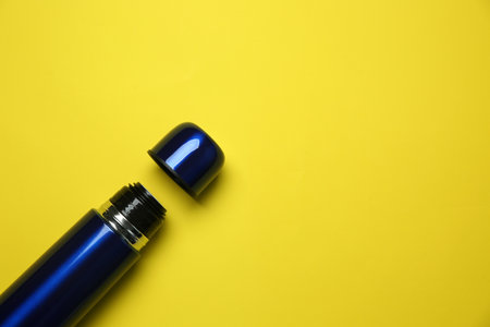 New modern flask and cup on yellow background, flat lay. Space for textの写真素材