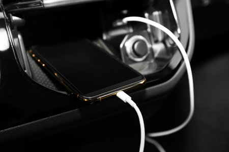 Smartphone with USB charging cable in modern carの写真素材