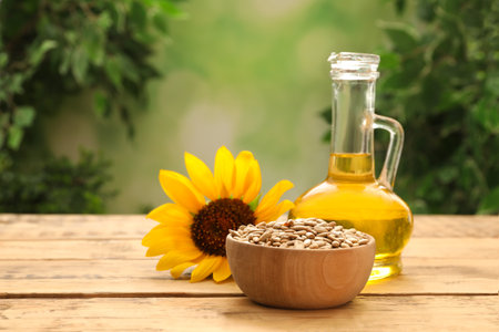 Sunflower, jug of oil and seeds on wooden table against blurred backgroundの写真素材