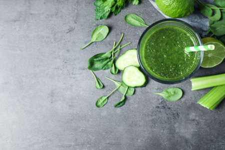 Green juice and fresh ingredients on gray table, flat lay. Space for textの写真素材