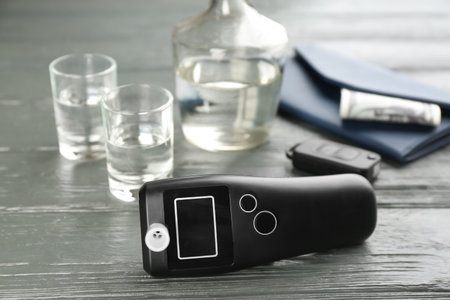 Modern breathalyser, car key, alcohol and wallet on gray wooden backgroundの写真素材