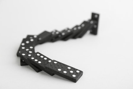 Black domino tiles falling on white backgroundの写真素材